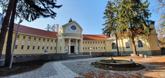 Извитата фасада на банята и калдъръменият двор пред входа.