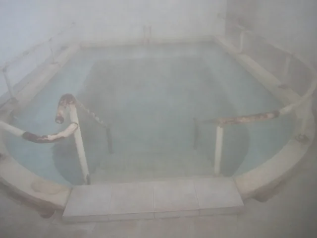 Шестоъгълен басейн с гореща минерална вода, обвит в пара.