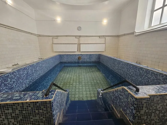 Басейнът с тъмносинята мозайка в отделението на банята.
