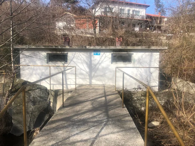 Входовете на двете отделения на банята, до мостчето над реката.