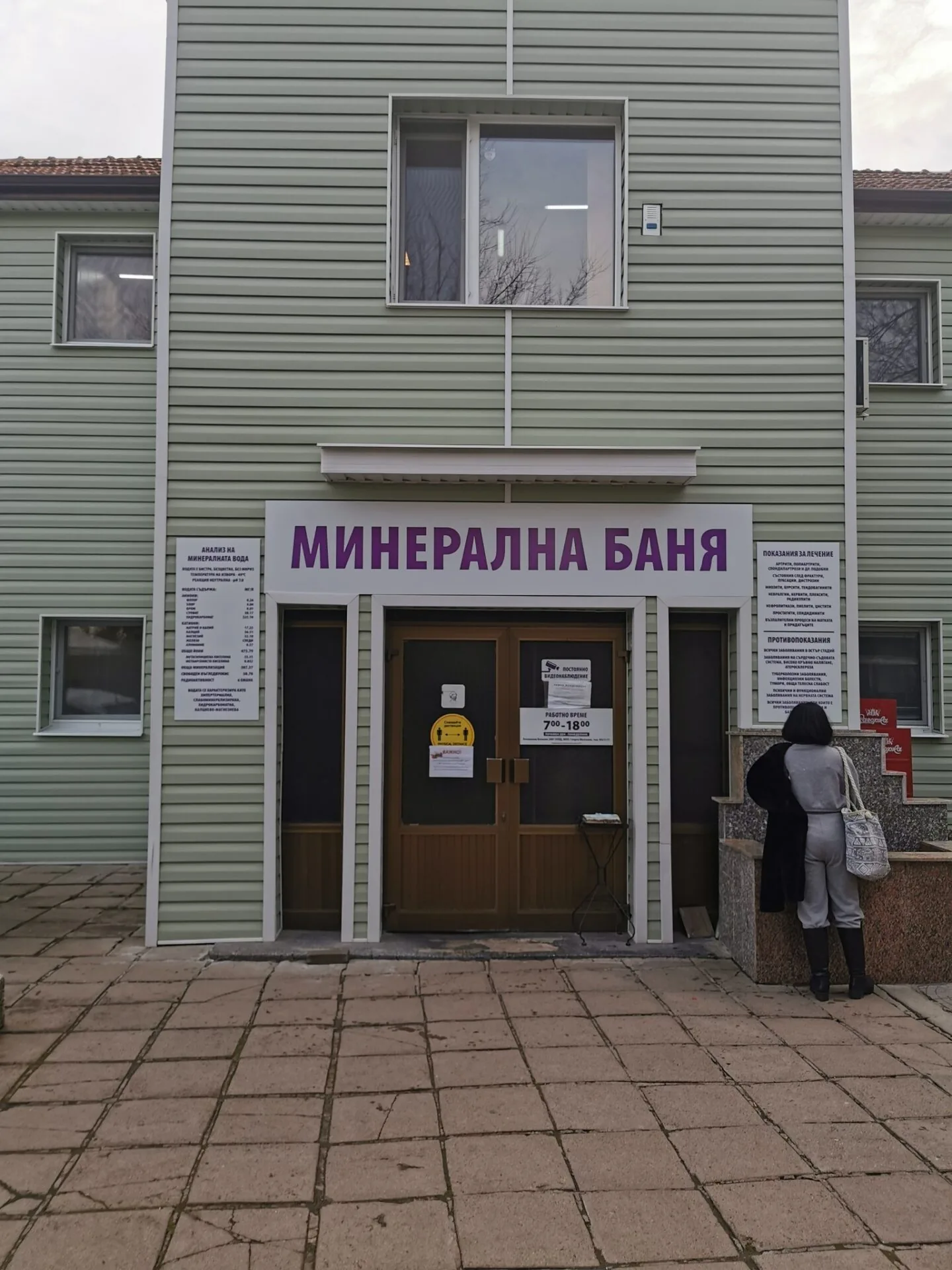 Входът на банята с надписа „Минерална баня“ и таблата с анализа на водата.