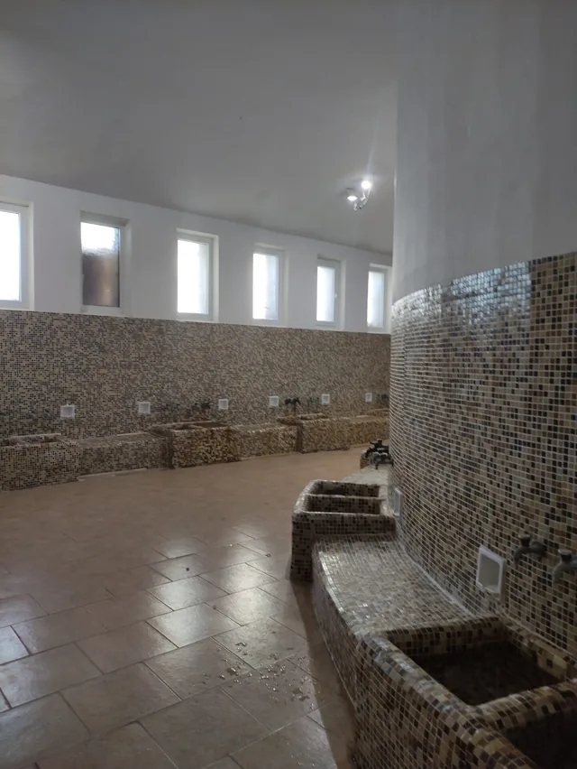 Залата с каменната стена и коритото с минерална вода.